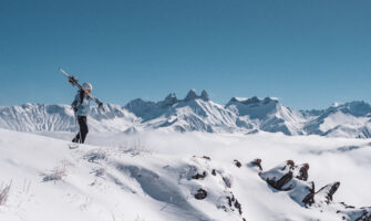 Photo d'une skieuse qui porte ses skis sur son épaule au corbier devant les aiguilles d'arves